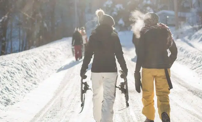 person holding snow ski blades while walking on snowy mountain during daytime