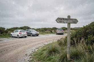Petit parking en gravier près de la pointe de Kadoran avec panneau de sentier côtier en Bretagne